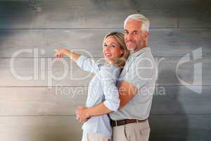 Composite image of happy couple smiling at camera and pointing