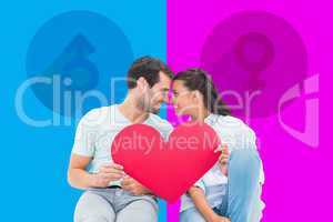 Composite image of cute couple sitting holding red heart