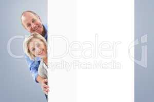 Composite image of mature couple smiling behind wall