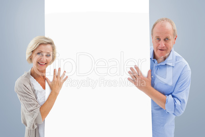 Composite image of mature couple smiling and holding card