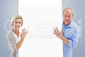 Composite image of mature couple smiling and holding card