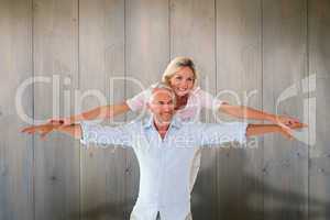 Composite image of smiling couple posing with arms out