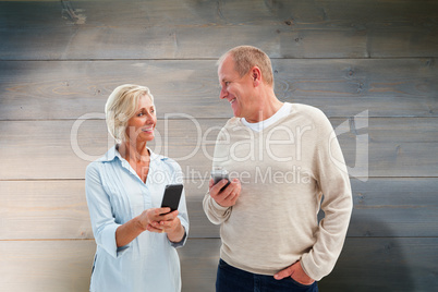 Composite image of happy mature couple using their smartphones