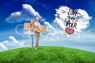 Composite image of happy couple holding moving boxes