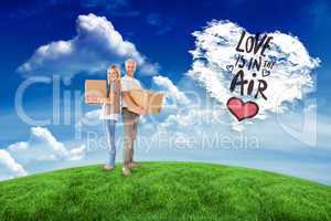 Composite image of happy couple holding moving boxes