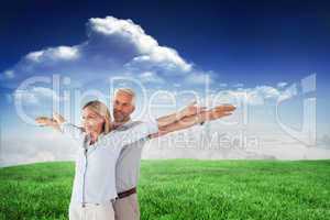 Composite image of happy couple standing with arms outstretched