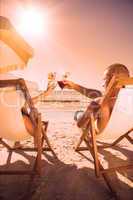 Couple clinking their glasses while relaxing on their deck chair