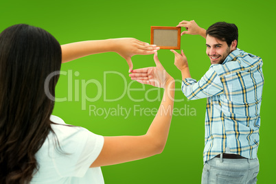 Composite image of happy young couple putting up picture frame