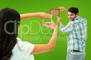 Composite image of happy young couple putting up picture frame