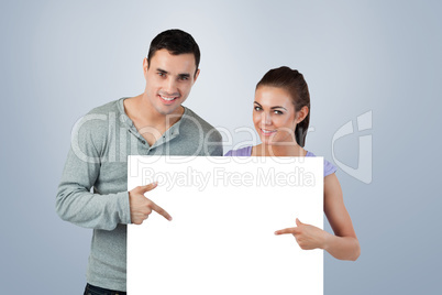 Composite image of young couple pointing at banner in front of t