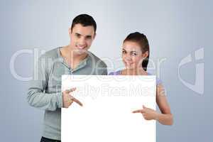 Composite image of young couple pointing at banner in front of t
