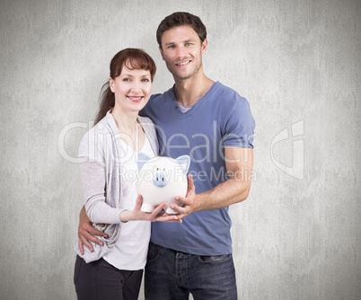 Composite image of couple holding a white piggy bank