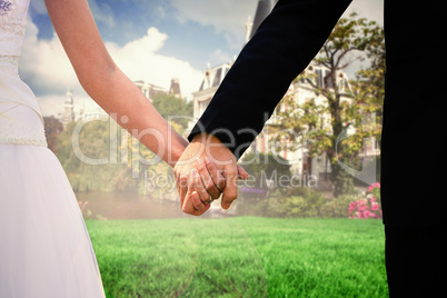 Composite image of mid section of newlywed couple holding hands