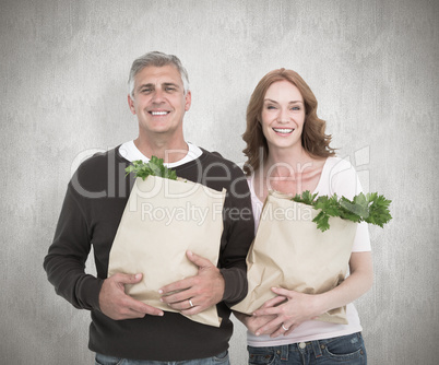 Composite image of casual couple holding grocery bags
