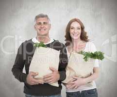 Composite image of casual couple holding grocery bags