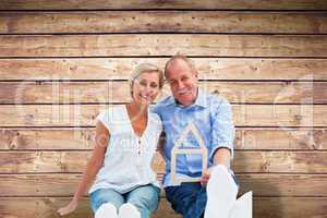 Composite image of happy mature couple holding a house shape