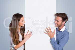 Composite image of happy young couple with blank board