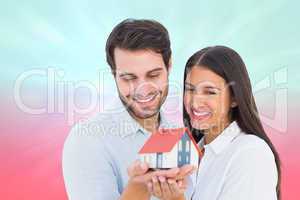 Composite image of attractive young couple holding a model house