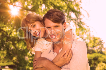 Man giving his pretty girlfriend a piggy back in the park smilin