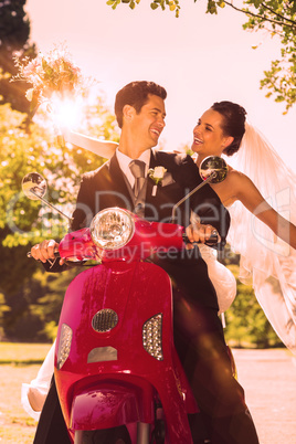 Newlywed couple sitting on scooter in park