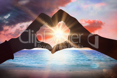 Composite image of couple making heart shape with hands