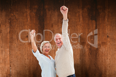 Composite image of happy mature couple cheering at camera