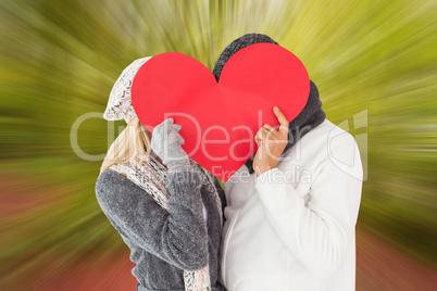 Composite image of couple in winter fashion posing with heart sh