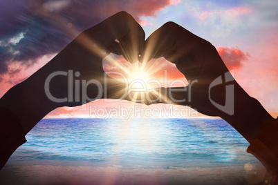 Composite image of woman making heart shape with hands