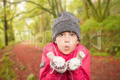 Composite image of wrapped up little girl blowing over hands