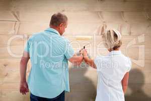 Composite image of happy older couple painting white wall