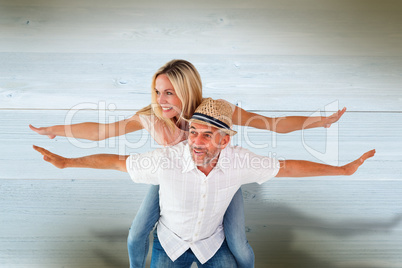 Composite image of happy man giving his partner a piggy back