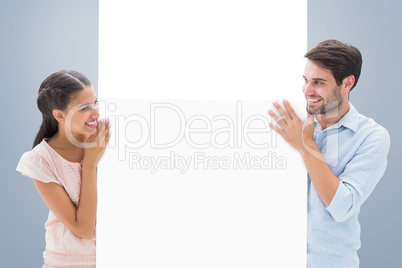 Composite image of attractive young couple smiling and holding p