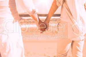 Couple on the beach looking out to sea holding hands