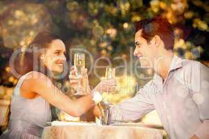 Couple with champagne flutes sitting at outdoor cafÃ©