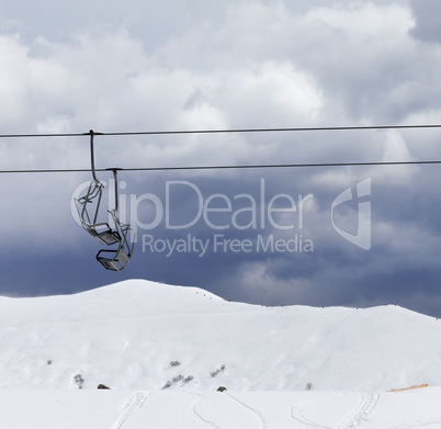 Chair lifts and off-piste slope at windy gray day