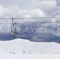 Chair lifts and off-piste slope at windy gray day