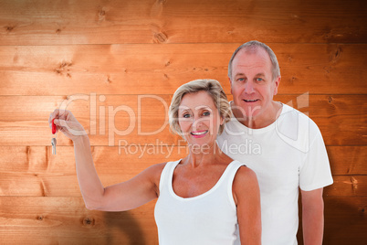 Composite image of mature couple smiling at camera with new hous