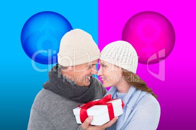 Composite image of casual couple in warm clothing holding gift