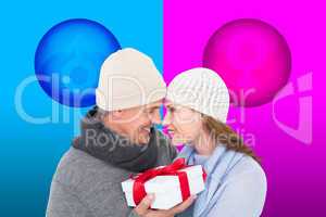 Composite image of casual couple in warm clothing holding gift