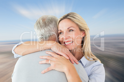 Composite image of happy couple standing and hugging