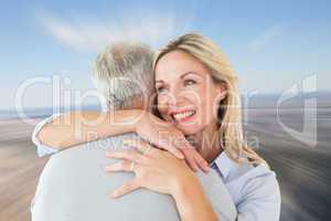 Composite image of happy couple standing and hugging