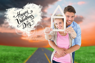 Composite image of young couple hugging and holding house outlin