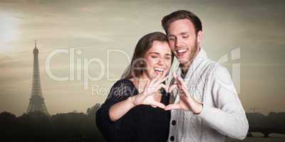 Composite image of happy couple forming heart with hands