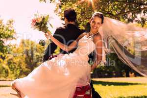 Newlywed couple sitting on scooter in park