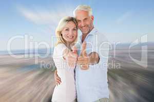 Composite image of smiling couple showing thumbs up together