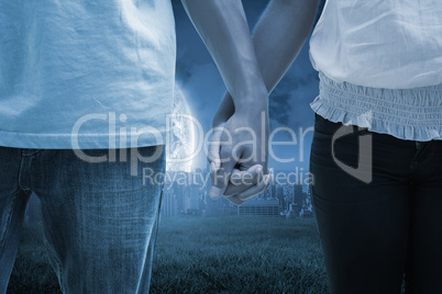 Composite image of young couple holding hands in the park