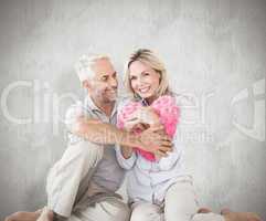 Composite image of happy couple sitting and holding heart pillow