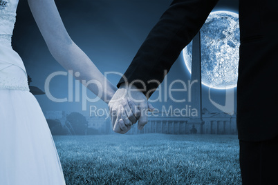 Composite image of mid section of newlywed couple holding hands