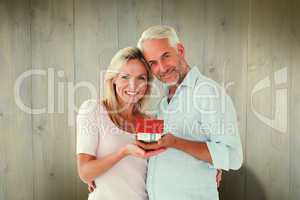 Composite image of happy couple holding miniature model house