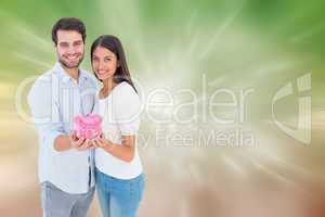 Composite image of happy couple showing their piggy bank